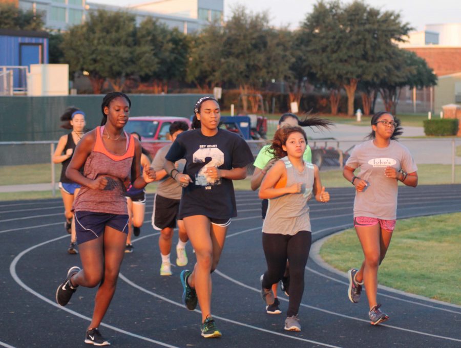 Girls cross country runners sprint across the track during practice. 