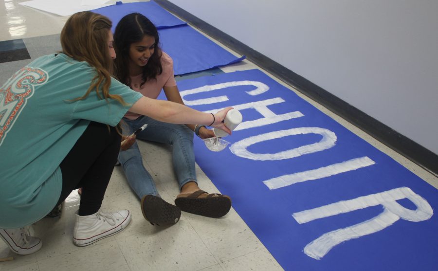 Seniors Jodie Johnson and Mita Dixit decorate a poster for choir's Red Ribbon Week hallway.