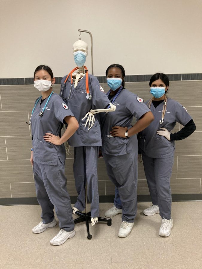 Plano West Clinicals students pose beside one of their learning tools--a properly masked model skeleton.
