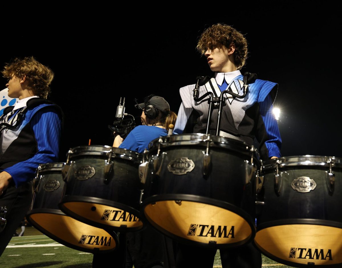 As the varsity football team takes on the Rock Hill High School hawks, junior Oliver Pringle waits for the signal to begin playing toward the student section while on the sideline Friday, Sept. 26. Each game, the drumline joins the cheerleaders to hype up the student section and cheer on the players.